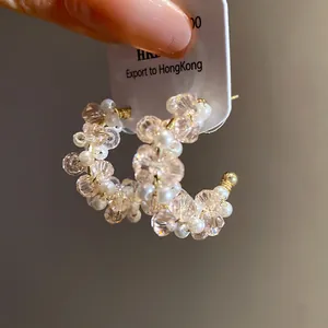 Close-up detail of elegant pink beaded C-shaped earrings featuring pearls and glass crystals