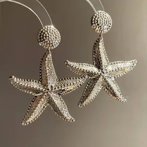 Detailed macro view of textured silver starfish drop earrings with refined metallic finish