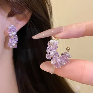 Detailed shot of elegant C-shaped earrings featuring purple glass beads and white pearls.