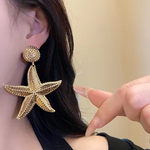 Oversized textured gold starfish drop earrings on model