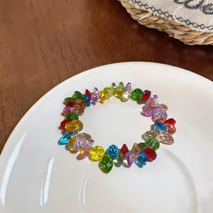 Close-up detail view of a colorful faceted acrylic beaded bracelet on a white ceramic plate