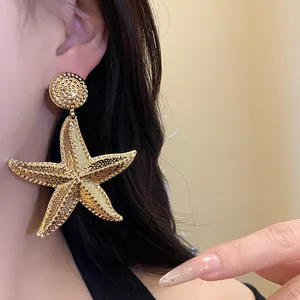 Detailed shot of large gold starfish dangle earrings with textured hammered finish