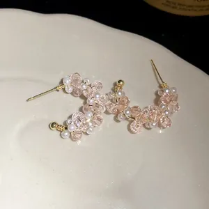 Macro view of elegant C-shaped earrings with pink glass beads and white pearls