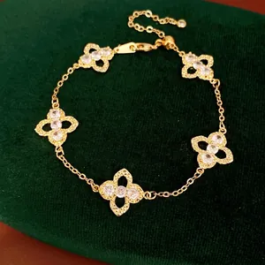 Elegant gold clover bracelet with sparkling white zircon flower charms on green velvet.