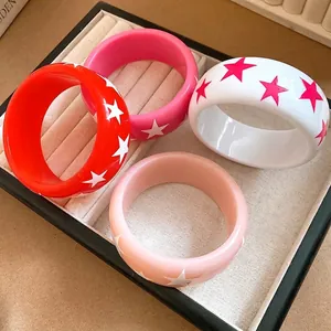 Set of vibrant resin bangles with star patterns, elegantly displayed on a jewelry tray.