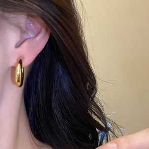 Primer plano de un pendiente de aro irregular dorado puesto en la oreja con estilo