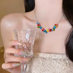 Colorful beaded stainless steel necklace worn by a model holding a glass cup close up