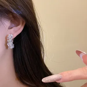 Detailed view of handmade clear glass beads and white pearl C-shaped earrings worn on an ear