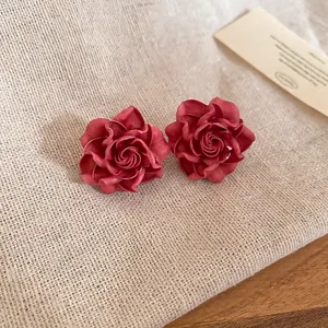 Close-up of elegant pink fabric flower stud earrings on linen texture background
