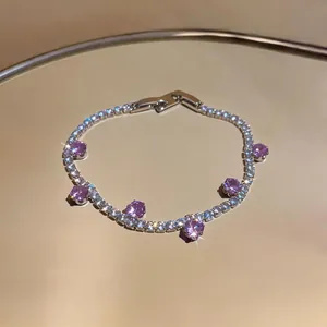 Detail shot of sparkling zircon bracelet with purple round stones on gold surface