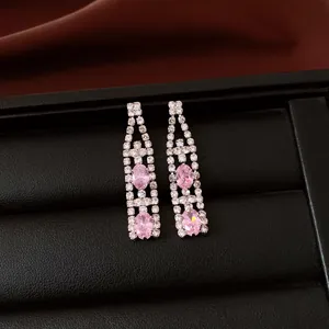 Dettaglio di orecchini pendenti vintage con cristalli ovali rosa in un portagioie nero