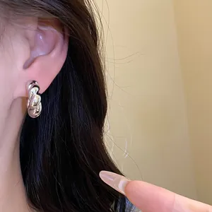 Primer plano de un pendiente de aro plateado irregular grueso usado en la oreja