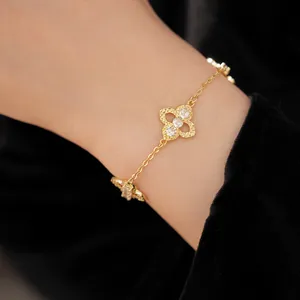 Close-up detail of an elegant gold-toned clover bracelet with sparkling zircon stones