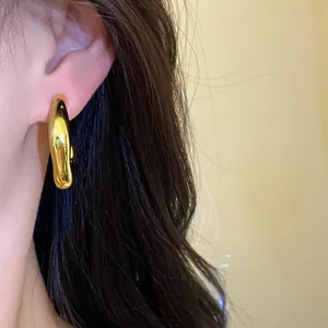 Detalle de un pendiente dorado irregular en la oreja para un look de moda elegante.