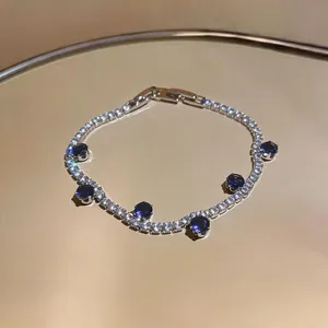 Close-up of luxury zircon tennis bracelet with blue stones on a gold mirror tray