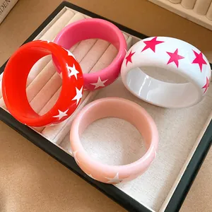 Detailed view of colorful resin bangles featuring star patterns in a jewelry tray.