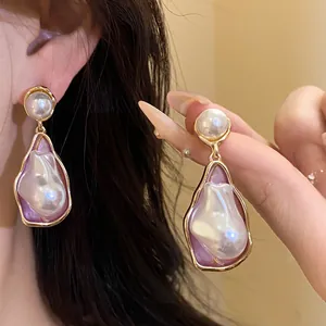 Close-up of vintage irregular pearl drop earrings with purple enamel and gold finish
