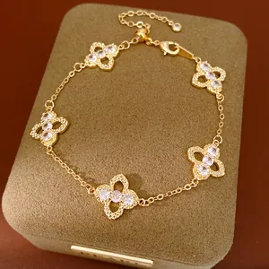 Close-up of gold-tone bracelet with zircon-encrusted clover motifs on a jewelry box.