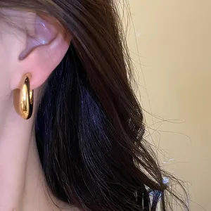 Primer plano detallado de un pendiente de aro grueso de oro brillante usado en la oreja