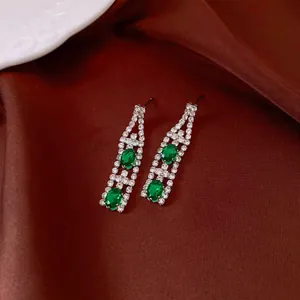 Eleganti orecchini vintage con zirconi verde smeraldo e cristalli su seta marrone.