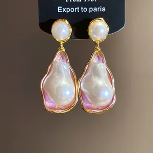 Close-up of vintage irregular pearl drop earrings with pink enamel and gold trim