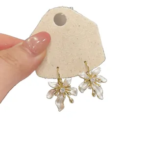 Elegant white enamel flower drop earrings with sparkling zircon centers on gold base