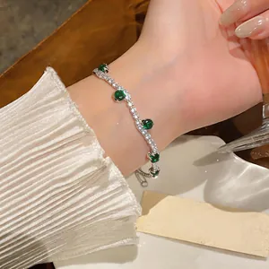 Close-up of a wavy zircon bracelet with sparkling green and white stones on a wrist
