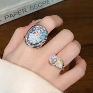 Primo piano di anelli minimalisti con conchiglia e perle indossati sulla mano