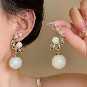 Close-up of French vintage palace style pearl earrings with crystal accents on a model