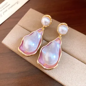 Macro detail of vintage style baroque pearl drop earrings with elegant pink enamel and gold trim