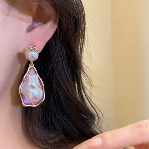 Close-up of vintage irregular pearl drop earrings with elegant gold frame detailing