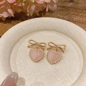Elegant sweet pink heart stud earrings featuring gold bow design and sparkling rhinestones