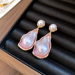 Detailed view of vintage irregular pearl earrings with gold-toned pink enamel setting.