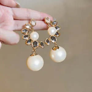Detailed view of vintage palace style gold earrings with large pearls and crystals.
