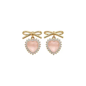 Elegant pink heart drop earrings featuring a gold bow and shimmering rhinestone halo detail.