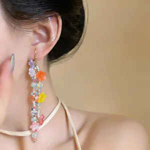 Detailed macro view of long dangling earrings with colorful resin flowers and beads