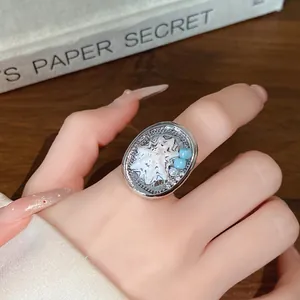 Vista dettagliata di un elegante anello in argento con conchiglia e perle blu sul dito