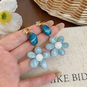 Close-up detail of fresh blue resin flower drop earrings with sparkling zircon studs