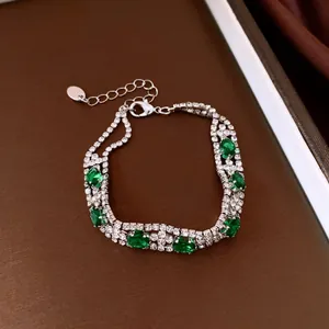 Dettaglio macro di un elegante bracciale vintage in argento con zirconi verdi ovali.