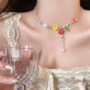 Detailed close-up of a colorful beaded necklace with resin flower charms and pearl drop.