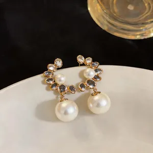 Close-up of French retro pearl earrings with crystals on a white ceramic plate.