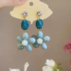 Detail of blue floral resin earrings with sparkling cubic zirconia studs