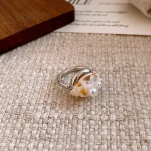 Primo piano di un anello in argento minimalista con conchiglia vera e perle bianche
