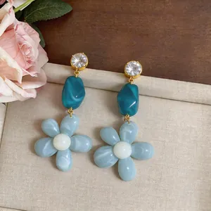 Close-up of elegant resin flower and zircon drop earrings with teal marble beads