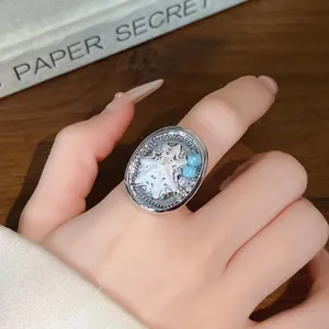 Primo piano di un anello in argento con dettagli in conchiglia e perle al dito.