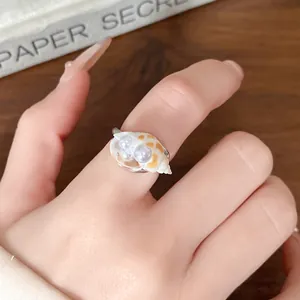 Primo piano di un anello a conchiglia con due perle eleganti su fascia regolabile