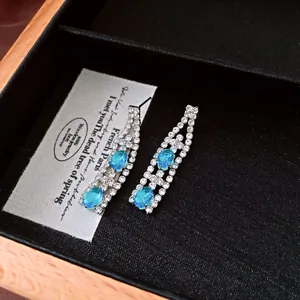Dettaglio macro di orecchini vintage in zircone con pietre preziose blu ovali.