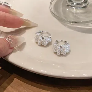 Dettaglio di orecchini a cerchio con perle stile francese, design elegante a cesto