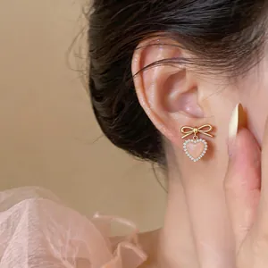 Detailed view of pink cat eye heart earring featuring a gold bow and rhinestone border