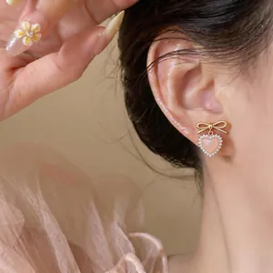 Detailed close-up of pink heart earring with cat eye stone and bow knot on ear